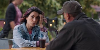 Movie still from “Demonic” (2021), directed by Neill Blomkamp – A woman sitting next to a man at a table with a drink; Close Up shot, Over the shoulder angle