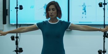 Movie still from “Demonic” (2021), directed by Neill Blomkamp – A woman standing in front of a screen with her arms outstretched; Medium shot, Low angle