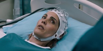 Movie still from “Demonic” (2021), directed by Neill Blomkamp – A woman wearing a white hat is laying on a blue bed; Close Up shot, Over the shoulder angle