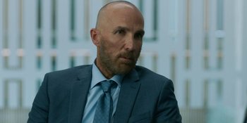 Movie still from “Demonic” (2021), directed by Neill Blomkamp – A man in a suit and tie looking at the camera; Close Up shot, Over the shoulder angle