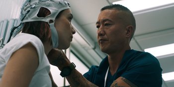 Movie still from “Demonic” (2021), directed by Neill Blomkamp – A man is putting makeup on another man's face; Close Up shot, Over the shoulder angle