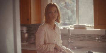 Movie still from “Demonic” (2021), directed by Neill Blomkamp – A woman standing in front of a kitchen sink; Medium shot, Low angle