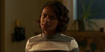 Movie still from “Demonic” (2021), directed by Neill Blomkamp – A woman in a white and gray shirt looking at the camera; Close Up shot, Over the shoulder angle