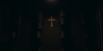Movie still from “Demonic” (2021), directed by Neill Blomkamp – A golden cross hanging on the side of a wall; Extreme Close Up shot, Overhead angle
