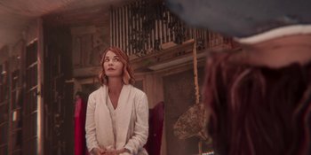 Movie still from “Demonic” (2021), directed by Neill Blomkamp – A woman sitting in a chair in front of a camera; Medium shot, Over the shoulder angle