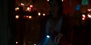 Movie still from “Demonic” (2021), directed by Neill Blomkamp – A woman holding a flashlight in a dark room; Medium shot, High angle
