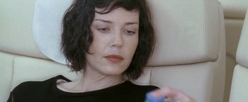 Movie still from “Demonlover” (2002), directed by Olivier Assayas – A person sitting on a couch holding a remote; Close Up shot, High angle