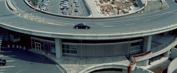 Movie still from “Demonlover” (2002), directed by Olivier Assayas – An aerial view of a car driving on a highway; Extreme Wide shot, Overhead angle