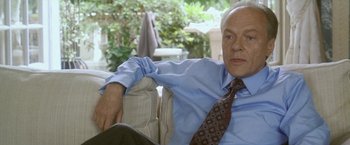 Movie still from “Demonlover” (2002), directed by Olivier Assayas – An older man sitting on top of a couch; Close Up shot, Over the shoulder angle