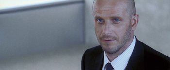Movie still from “Demonlover” (2002), directed by Olivier Assayas – A person wearing a suit and tie; Close Up shot, Low angle