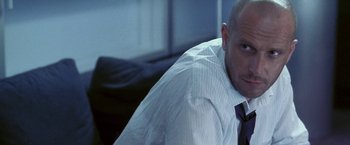 Movie still from “Demonlover” (2002), directed by Olivier Assayas – A bald man in a white shirt and a black tie; Close Up shot, Low angle