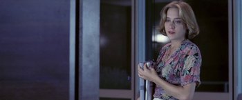 Movie still from “Demonlover” (2002), directed by Olivier Assayas – A woman standing in front of a building holding a phone; Medium shot, Over the shoulder angle