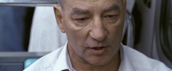 Movie still from “Demonlover” (2002), directed by Olivier Assayas – An older man in a white dress shirt; Close Up shot, Over the shoulder angle