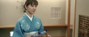Movie still from “Demonlover” (2002), directed by Olivier Assayas – A woman in a blue kimono holding a bowl of water; Medium shot, Over the shoulder angle