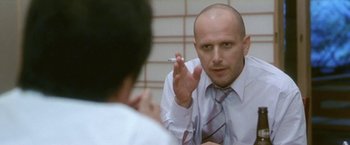 Movie still from “Demonlover” (2002), directed by Olivier Assayas – A man in a white dress shirt and tie holding up a cigarette; Close Up shot, Low angle