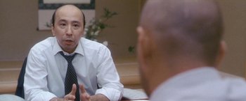 Movie still from “Demonlover” (2002), directed by Olivier Assayas – A man in a white shirt and a tie talking to another man in a white shirt and a black tie; Close Up shot, Over the shoulder angle