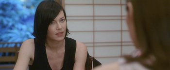 Movie still from “Demonlover” (2002), directed by Olivier Assayas – A woman sitting in front of a mirror in front of a wall; Close Up shot, Over the shoulder angle