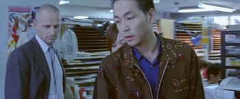 Movie still from “Demonlover” (2002), directed by Olivier Assayas – A man and a woman standing next to each other in a room; Medium shot, Low angle