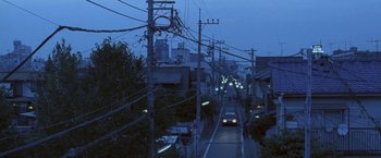Movie still from “Demonlover” (2002), directed by Olivier Assayas – A car driving down a street at night; Extreme Wide shot, High angle