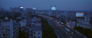 Movie still from “Demonlover” (2002), directed by Olivier Assayas – An aerial view of a city at night with cars driving on the road; Extreme Wide shot, High angle