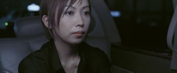 Movie still from “Demonlover” (2002), directed by Olivier Assayas – A woman sitting in the back seat of a car; Close Up shot, High angle