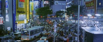 Movie still from “Demonlover” (2002), directed by Olivier Assayas – A busy city street filled with lots of traffic; Extreme Wide shot, High angle
