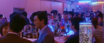 Movie still from “Demonlover” (2002), directed by Olivier Assayas – A group of people sitting at a table in a room; Medium shot, High angle