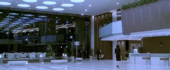 Movie still from “Demonlover” (2002), directed by Olivier Assayas – People are standing in a lobby of a building; Extreme Wide shot, High angle