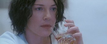 Movie still from “Demonlover” (2002), directed by Olivier Assayas – A person holding a glass of water; Close Up shot, High angle