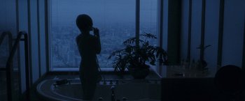 Movie still from “Demonlover” (2002), directed by Olivier Assayas – A woman standing in front of a window in a bathroom; Wide shot, High angle