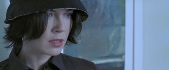 Movie still from “Demonlover” (2002), directed by Olivier Assayas – A person wearing a hat and looking at the camera; Close Up shot, Low angle