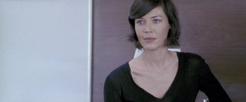 Movie still from “Demonlover” (2002), directed by Olivier Assayas – A woman with short black hair wearing a black shirt; Close Up shot, Over the shoulder angle