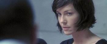 Movie still from “Demonlover” (2002), directed by Olivier Assayas – A person with short hair looking into a mirror; Close Up shot, Over the shoulder angle