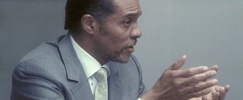 Movie still from “Demonlover” (2002), directed by Olivier Assayas – A person wearing a suit holding a cell phone; Close Up shot, Over the shoulder angle