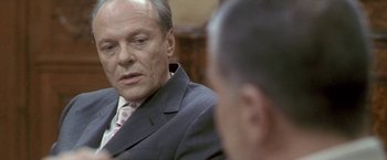 Movie still from “Demonlover” (2002), directed by Olivier Assayas – A man wearing a suit and tie talking to another man wearing a suit and tie; Close Up shot, Over the shoulder angle