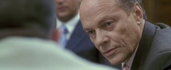 Movie still from “Demonlover” (2002), directed by Olivier Assayas – A person wearing a suit and tie; Close Up shot, Over the shoulder angle