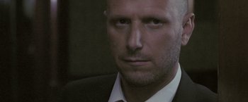 Movie still from “Demonlover” (2002), directed by Olivier Assayas – A person wearing a suit and tie; Close Up shot, Low angle