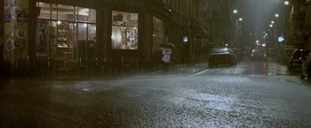 Movie still from “Demonlover” (2002), directed by Olivier Assayas – A person holding an umbrella while standing in the rain; Extreme Wide shot, High angle