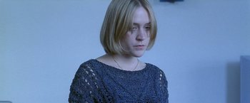 Movie still from “Demonlover” (2002), directed by Olivier Assayas – A woman with short blonde hair wearing a blue sweater; Close Up shot, High angle