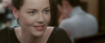 Movie still from “Demonlover” (2002), directed by Olivier Assayas – A woman's face in front of a group of people; Close Up shot, Over the shoulder angle