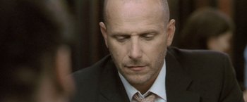 Movie still from “Demonlover” (2002), directed by Olivier Assayas – A man in a suit and tie looking down; Close Up shot, Low angle