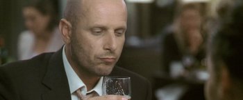 Movie still from “Demonlover” (2002), directed by Olivier Assayas – A man in a suit and tie holding a glass of wine; Close Up shot, Low angle