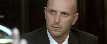 Movie still from “Demonlover” (2002), directed by Olivier Assayas – A man in a black suit and white tie; Close Up shot, Over the shoulder angle