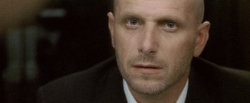 Movie still from “Demonlover” (2002), directed by Olivier Assayas – A person wearing a suit and tie; Close Up shot, Low angle