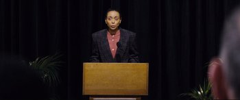 Movie still from “Denial” (2016), directed by Mick Jackson – A man standing at a podium in front of a microphone; Medium shot, High angle