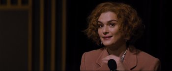 Movie still from “Denial” (2016), directed by Mick Jackson – A woman with red curly hair standing in front of a microphone; Close Up shot, Over the shoulder angle
