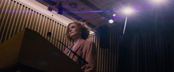 Movie still from “Denial” (2016), directed by Mick Jackson – A woman standing in front of a microphone in a room; Medium shot, Low angle