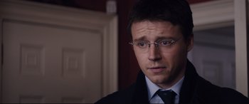 Movie still from “Denial” (2016), directed by Mick Jackson – A person wearing a suit and glasses; Close Up shot, Over the shoulder angle
