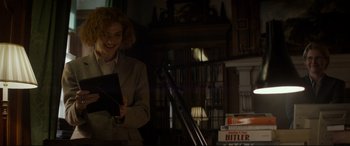 Movie still from “Denial” (2016), directed by Mick Jackson – A woman holding a book in a room filled with bookcases; Medium shot, Low angle