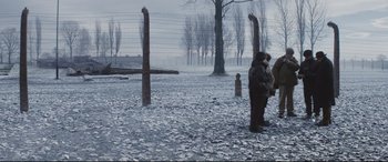 Movie still from “Denial” (2016), directed by Mick Jackson – A person standing in a field near barbed wire; Extreme Wide shot, High angle